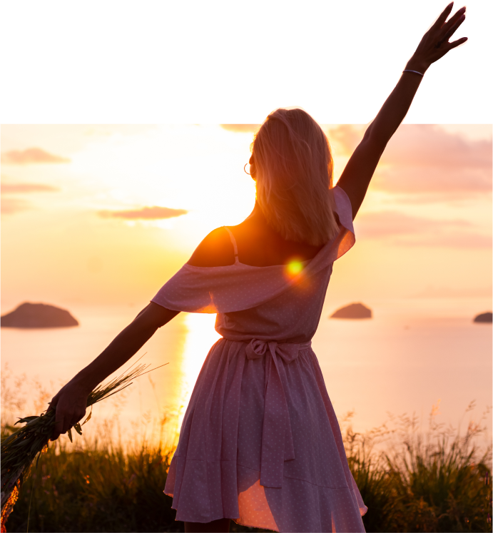 A woman in a light dress enjoying sunset by the sea, symbolizing affordable fashion.